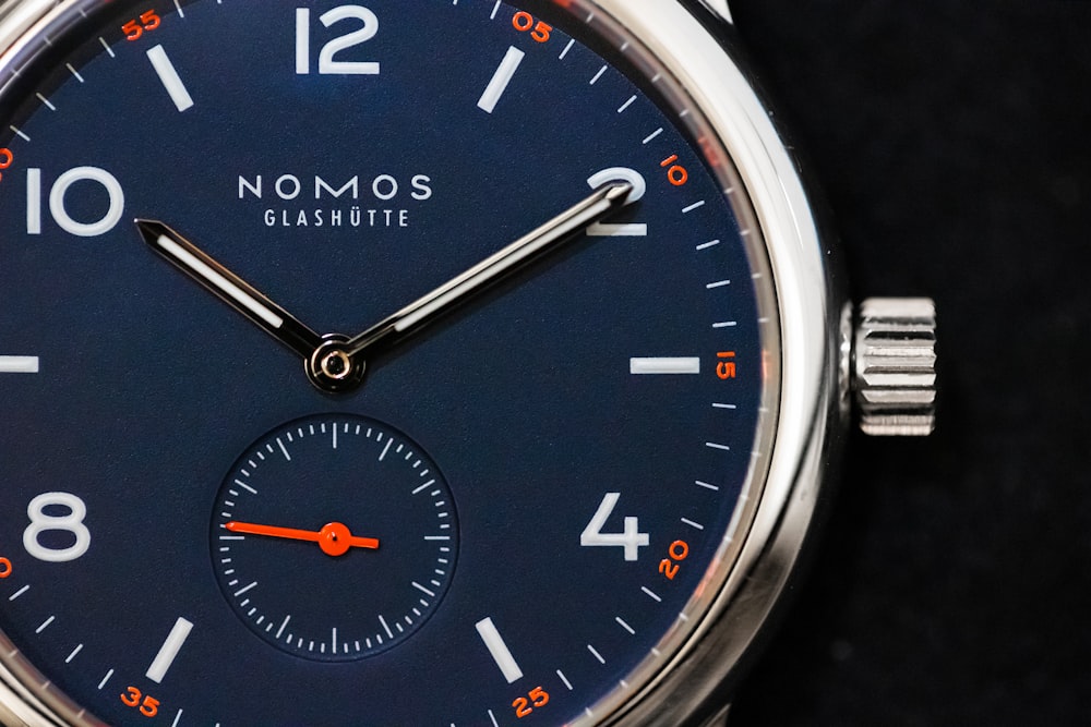 round silver-colored Nomos watch at 10:10
